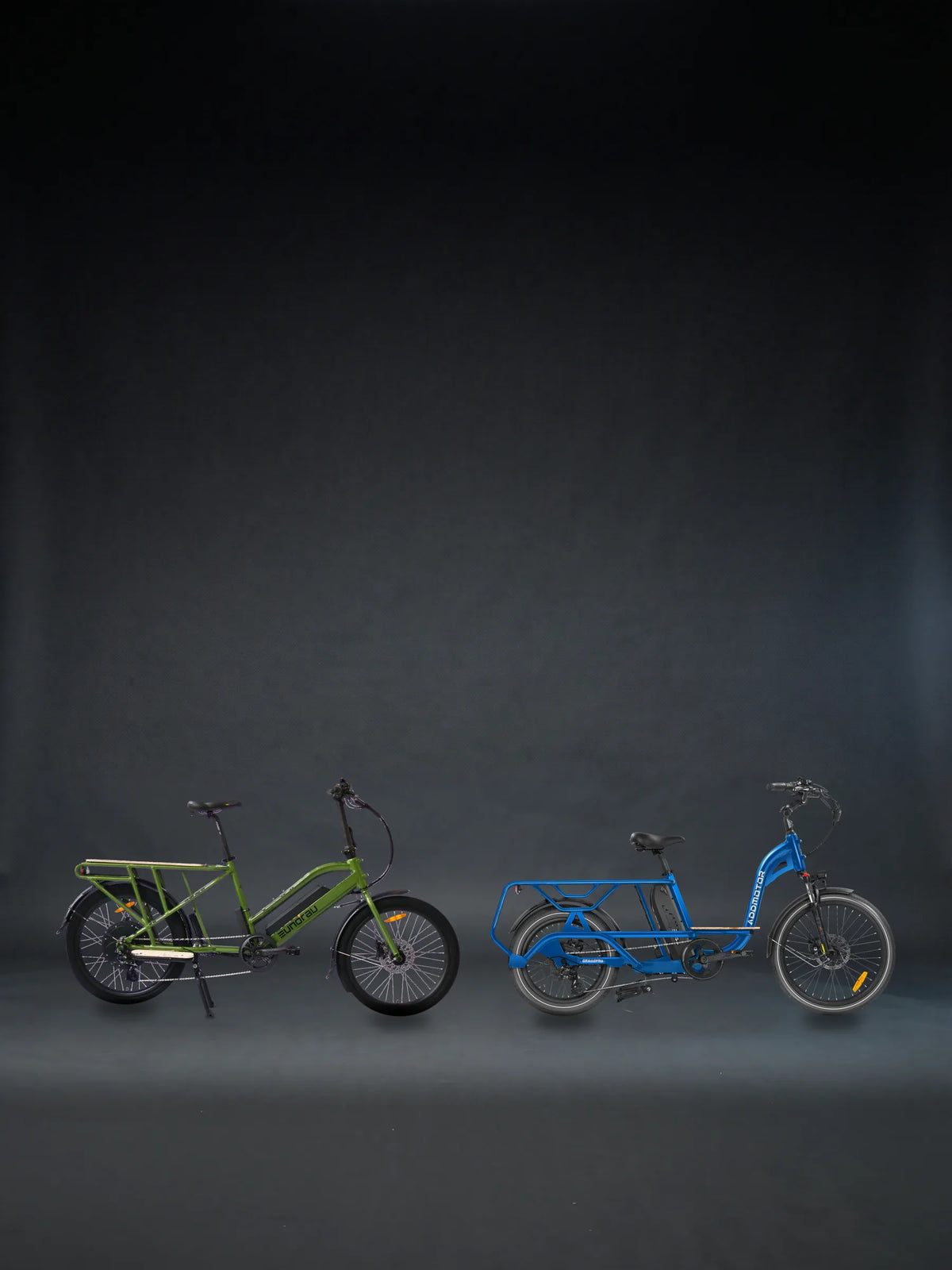 Two cargo bikes we sell like the Aventon Abound SR, the Eunorau MAX-CARGO 2.0 in Green and the Addmotor Graoopro in Neptune Blue, side by side on a graphite studio floor, each in its maker's own photograph