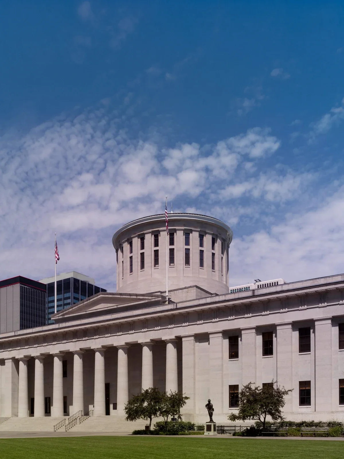 The Ohio Statehouse in Columbus, its stone colonnade and windowed drum under a clear summer sky