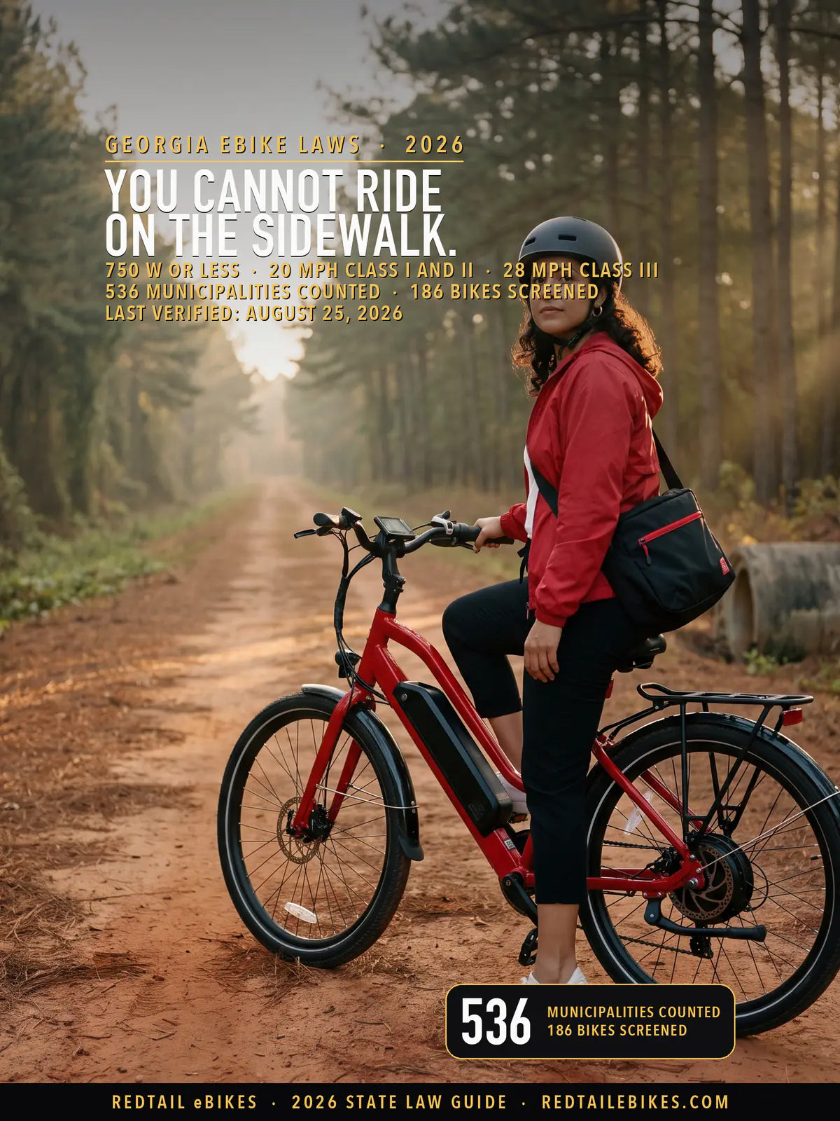 Rider in a fitted helmet on a red electric commuter bike with a downtube battery on a pine-shaded Georgia rail trail at golden hour, red clay shoulder and longleaf pines receding behind