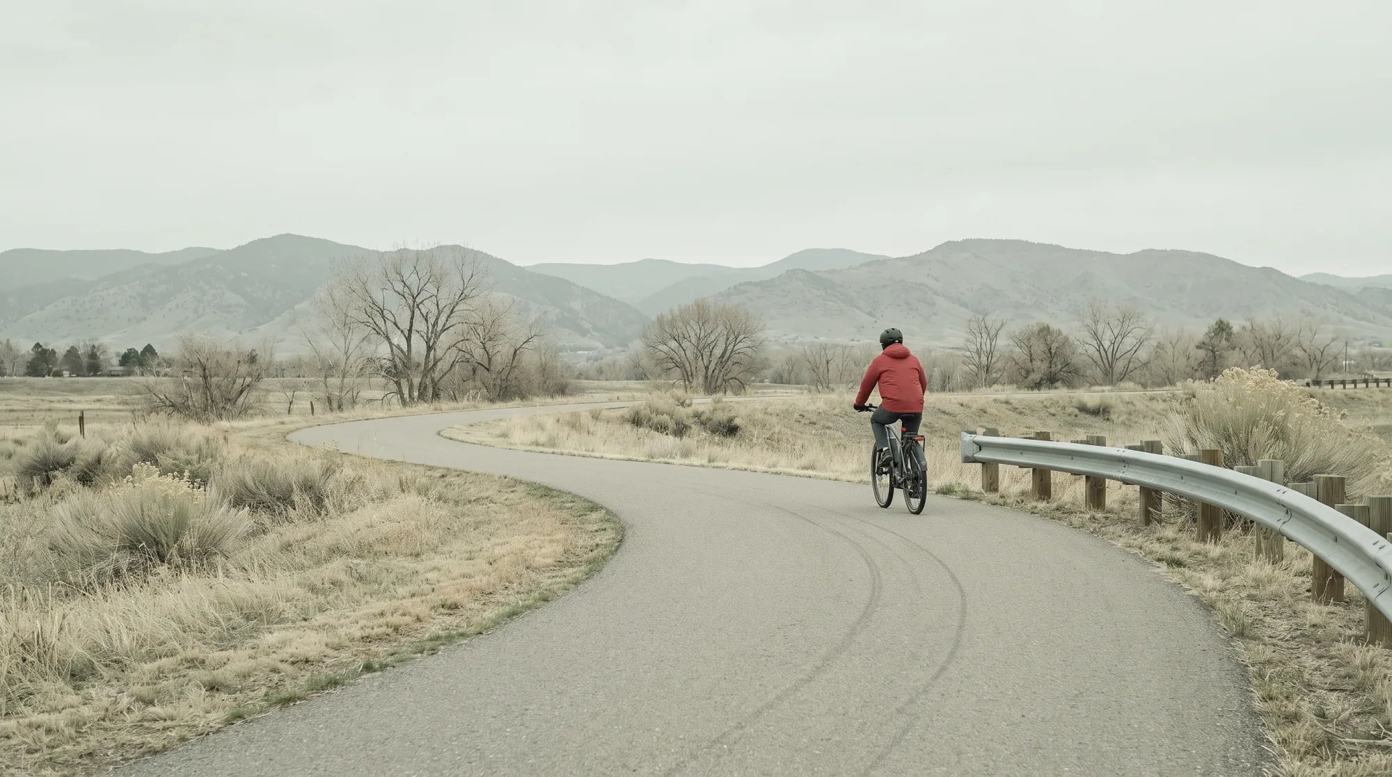 Cyclist riding an electric bike on a paved mountain trail in Colorado with peaks in the distance