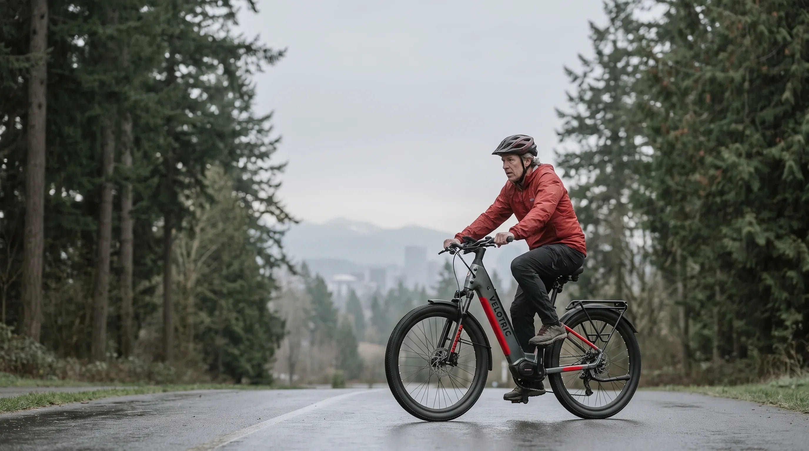 Rider on an electric bike on a Pacific Northwest shared-use trail with evergreen forest and mountains behind
