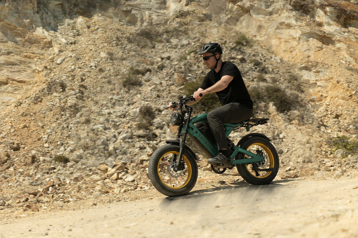 Smartravel Raptor ST202 GPS Fat Tire Electric Bike in green, ridden along a gravel track below a rocky hillside
