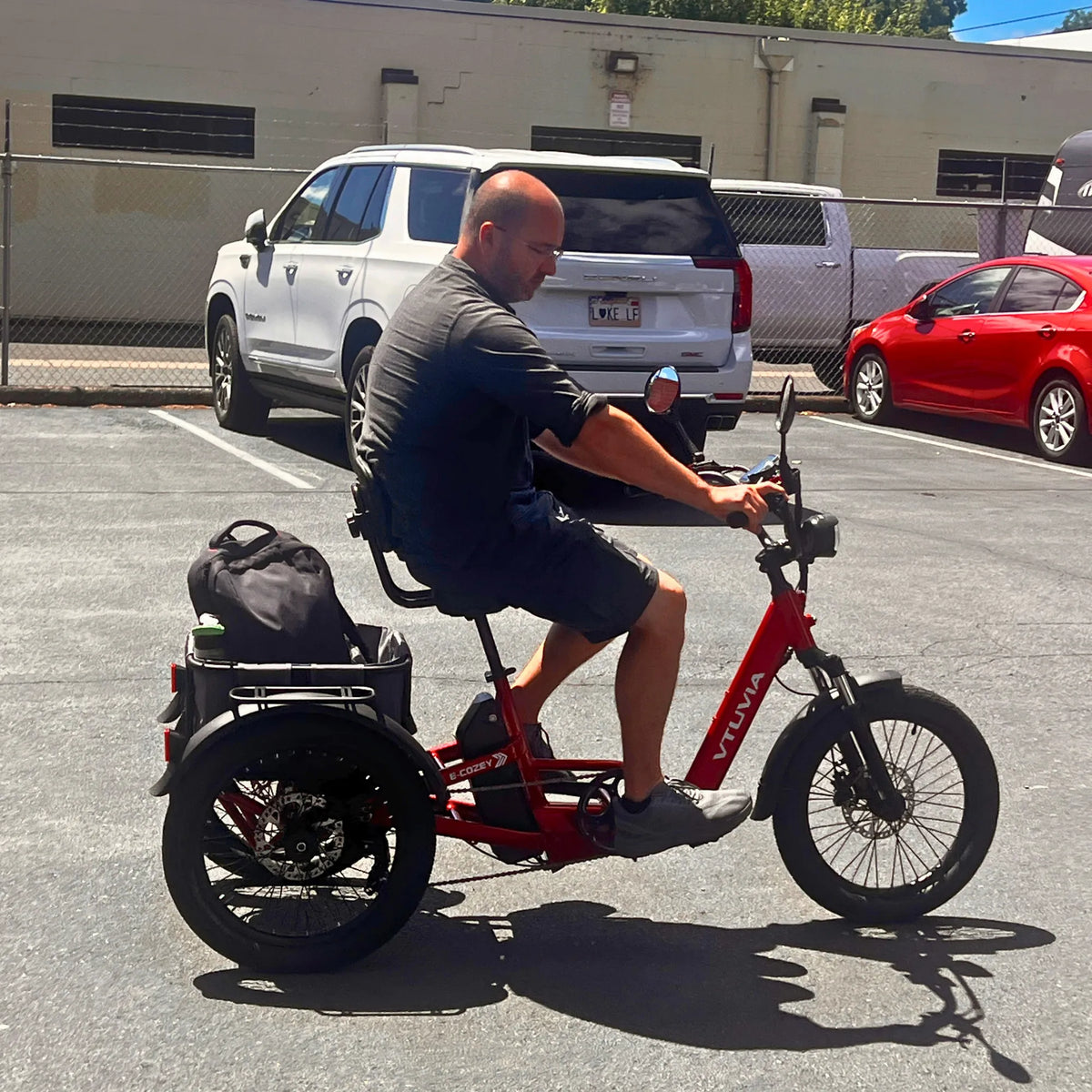 Rider on a red E-Cozy trike with a bag in the rear basket