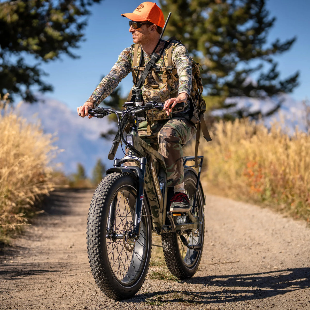 Hunter riding a camo SN100 down a gravel forest road