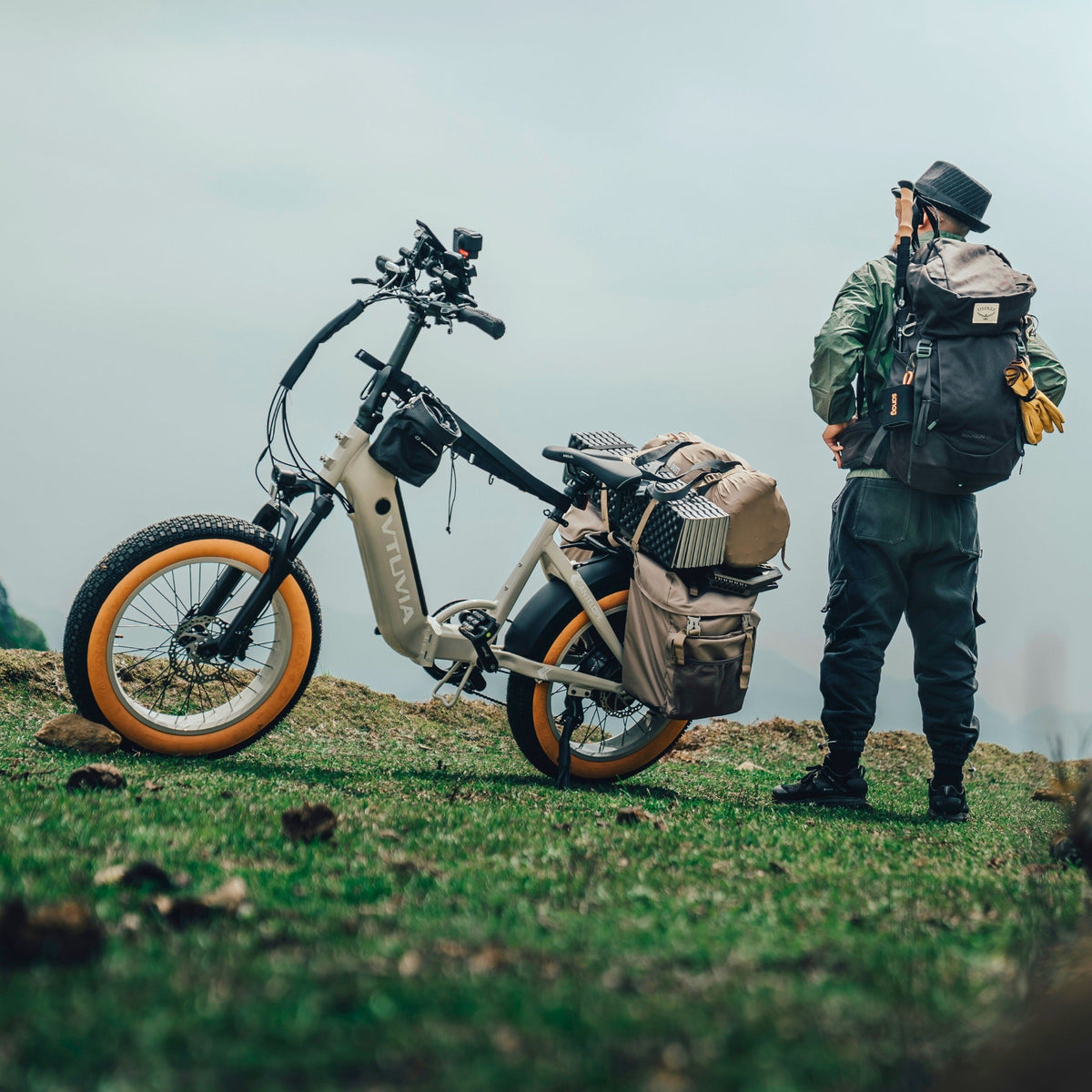 Hiker standing beside a loaded cream SX20 on a grassy hilltop