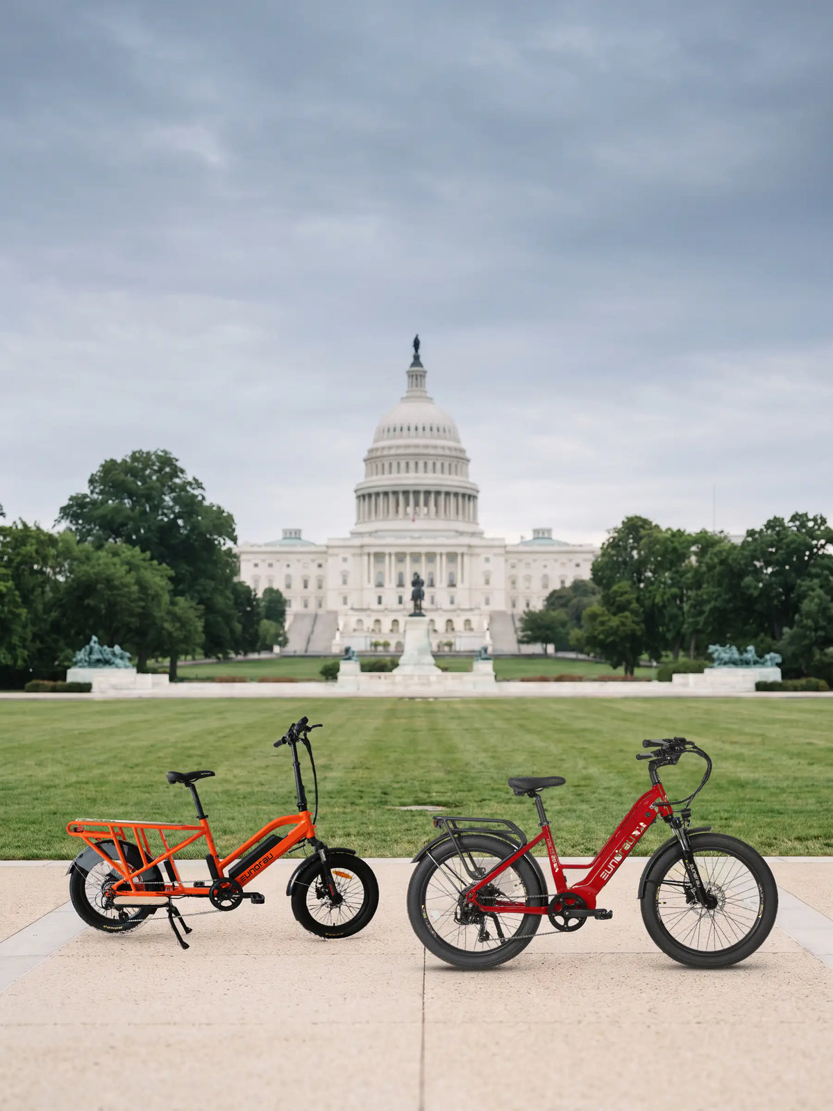 Electric bike laws by state 2026: an orange Eunorau G30-CARGO 2.0 and a red Eunorau META26 parked on a sidewalk of the National Mall, the United States Capitol behind them