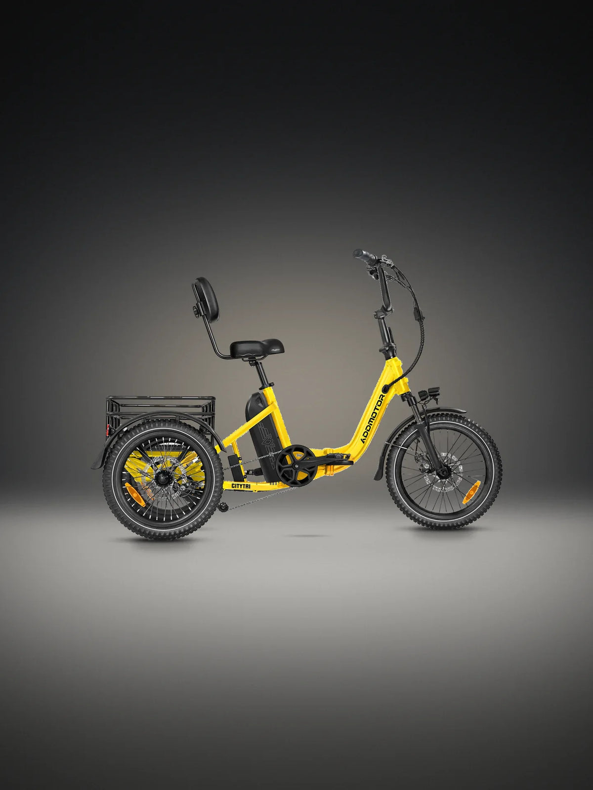 Addmotor Citytri E-310 folding electric trike in Yellow on a lit studio floor against a dark wall, side view, with its yellow folding step-through frame, the backrest saddle, the rear basket and the three knobbed tyres