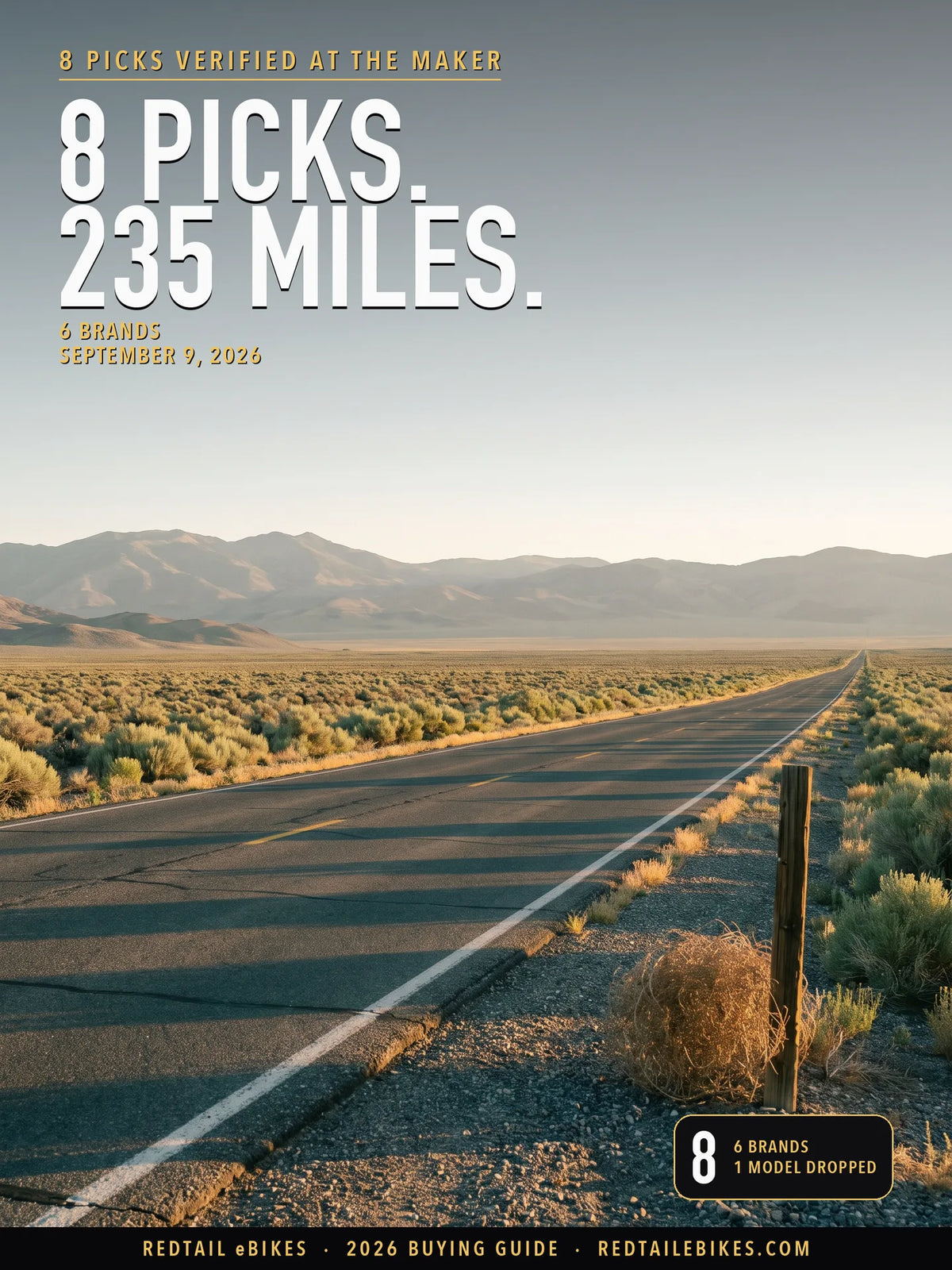 A loaded touring-style electric bike parked at an overlook at golden hour with an open highway receding into hazy hills behind it