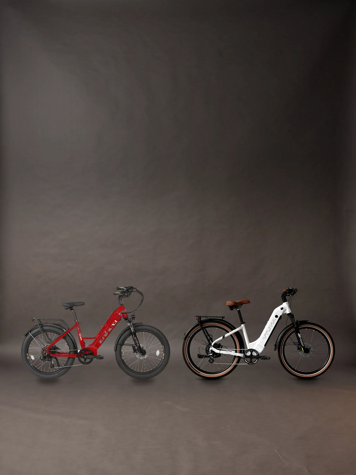 Aventon Pace 5 REC review banner: two bikes we sell like it, the Eunorau META26 in Deep Crimson and the VTUVIA Zeal XT8 in Glacier White, each its maker's own photograph, standing side by side on the charcoal paper floor of a photographic studio