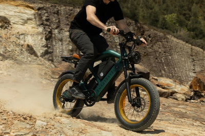 Smartravel Raptor ST202 GPS Fat Tire Electric Bike in green, ridden across a dusty dirt slope below a rock face
