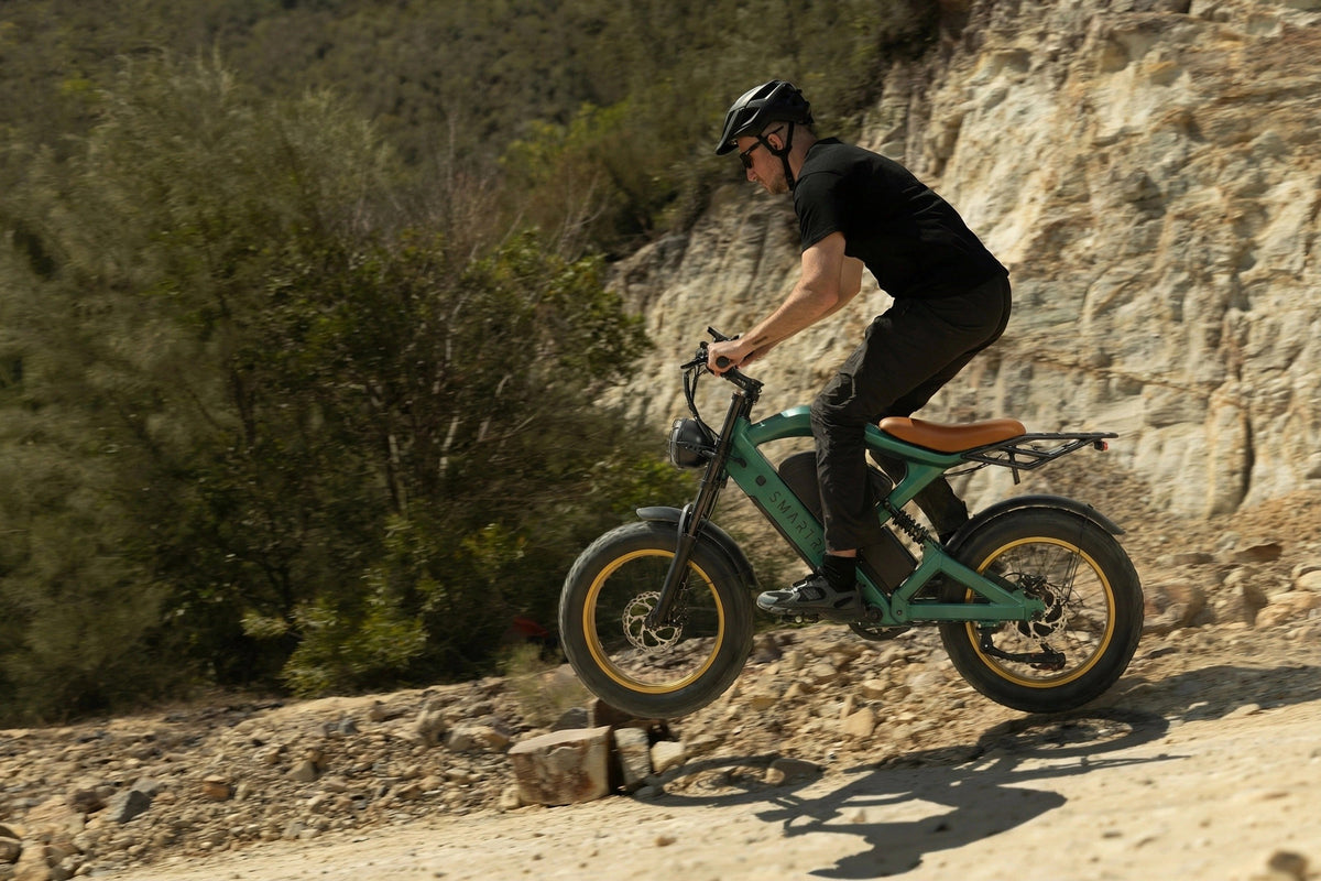 Smartravel Raptor ST202 GPS Fat Tire Electric Bike in green, ridden over rocks at the foot of a sandstone bank
