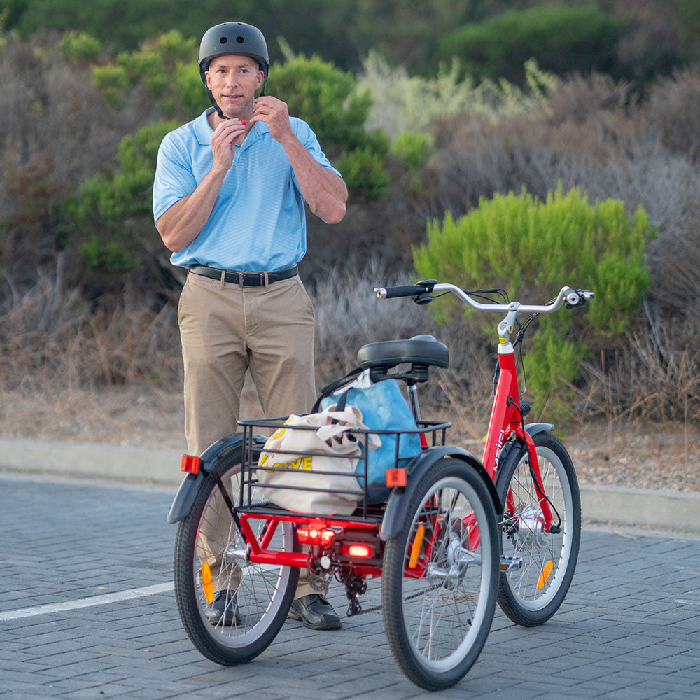 A rider buckles a helmet beside a red MG708 Hera with shopping bags in its rear basket