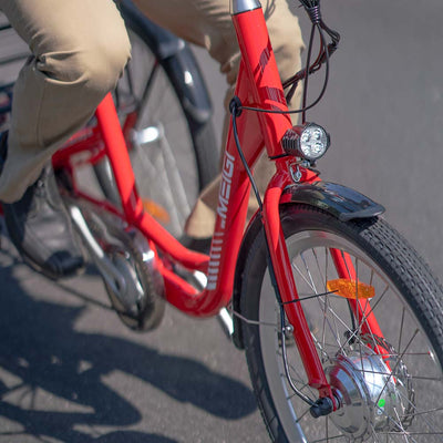 Close-up of a rider pedaling a red MG708 Hera, its headlight and front wheel in view