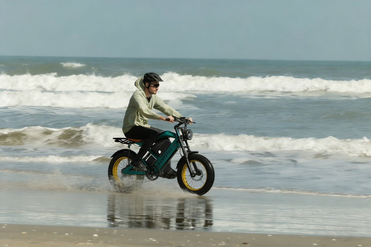 Smartravel Raptor ST202 GPS Fat Tire Electric Bike in green, ridden through shallow surf along a beach
