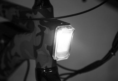 The headlight lit at night on a camouflage bike