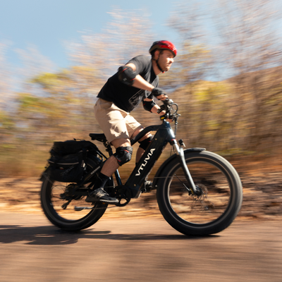A rider on a VTUVIA fat-tire bike with the pannier set fitted, on a dirt road