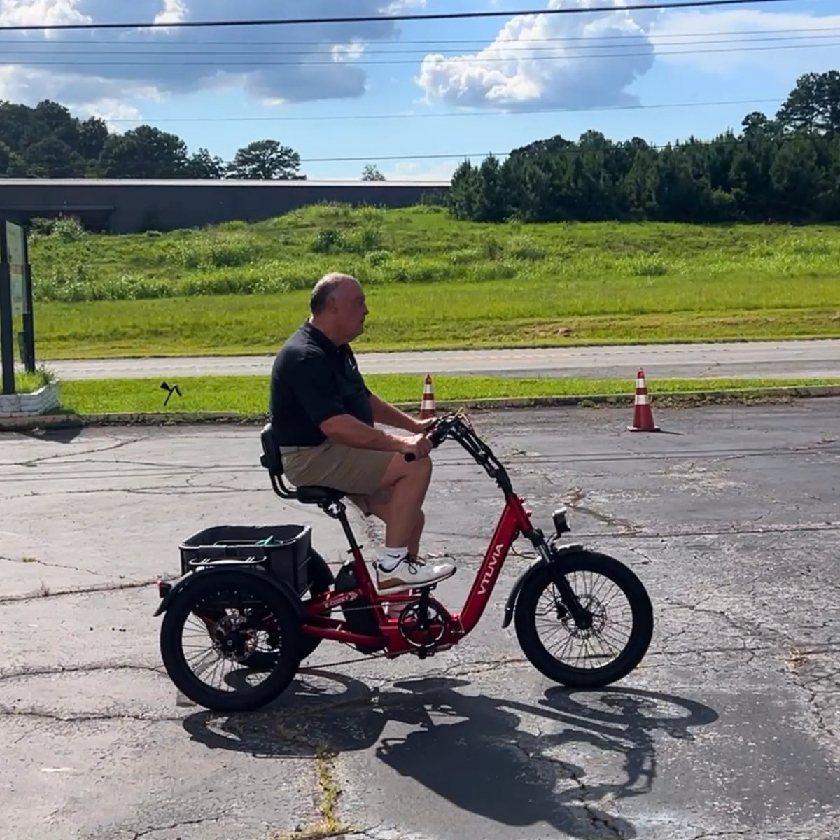 Rider on a red E-Cozy trike beside a grass verge