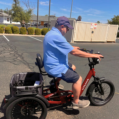 Rider on a red E-Cozy trike in a parking lot