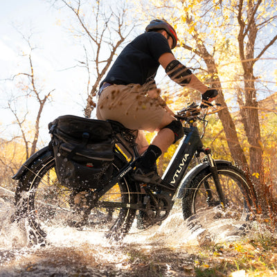 Rider splashing through a creek on a Gemini with panniers