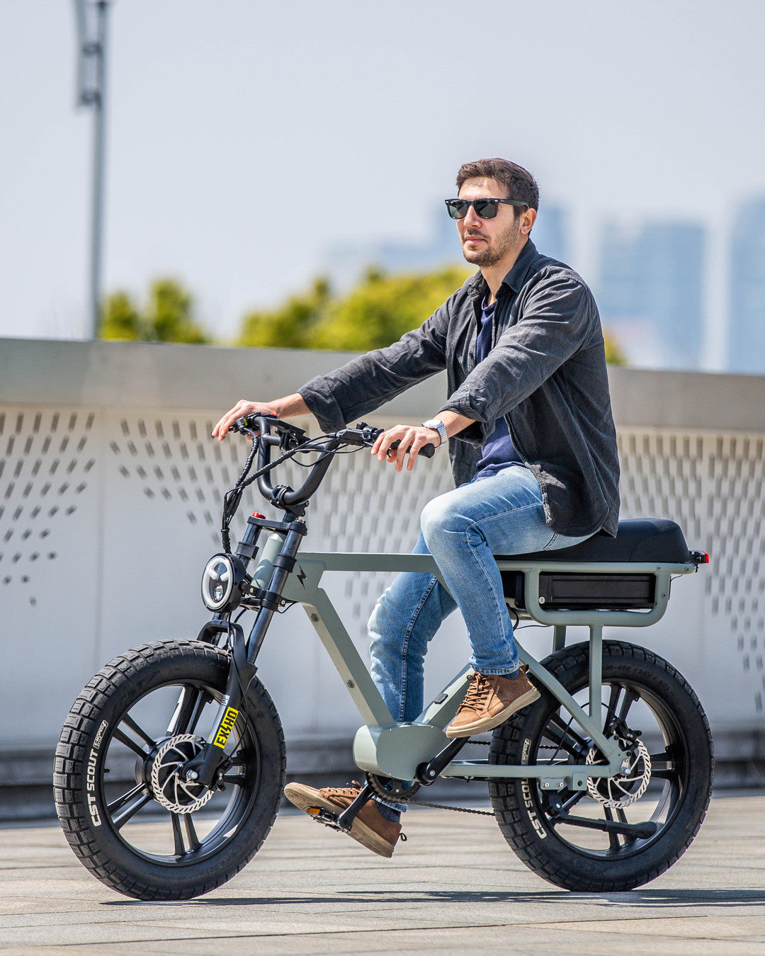 A rider on a Eunorau fat-tire e-bike crossing a sunny city plaza