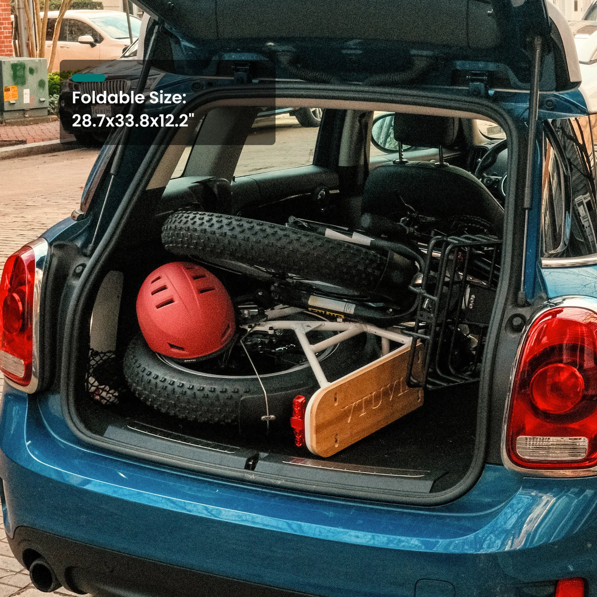SF20H folded flat in a hatchback trunk beside a red helmet