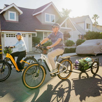 Two riders on Zeal bikes, the white XT8 towing a trailer of groceries
