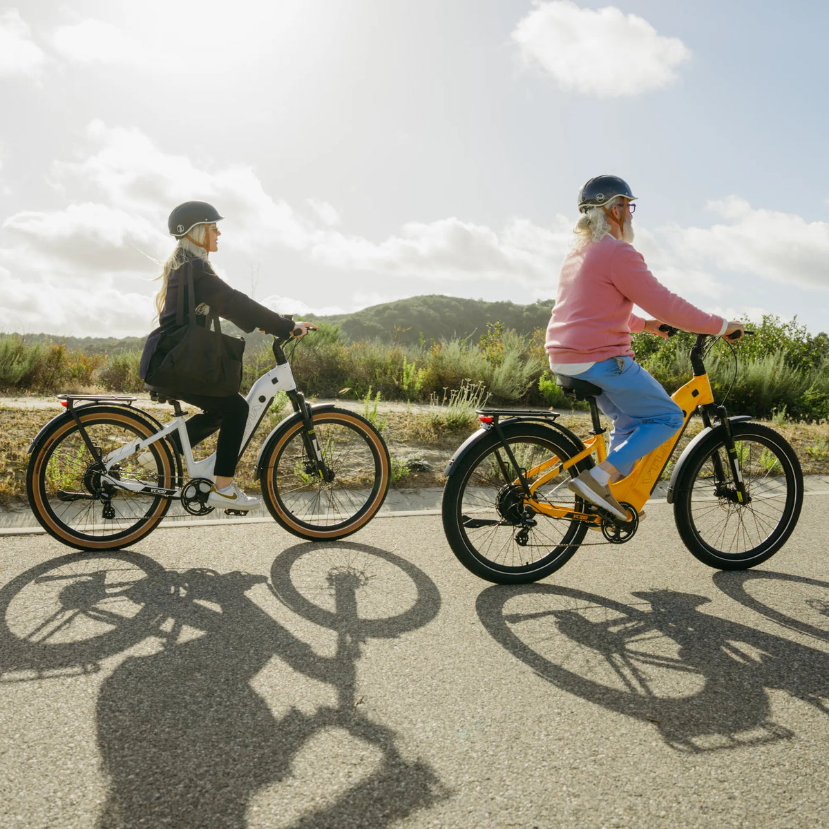 Two riders on Zeal bikes on a coastal path, long shadows